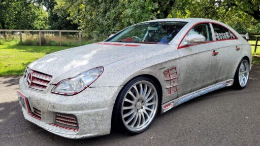 A crystal-encrusted 2005 Mercedes CLS500 with a sparkling exterior and luxurious features, including a V8 engine and red leather interior, is up for sale at £7,000.