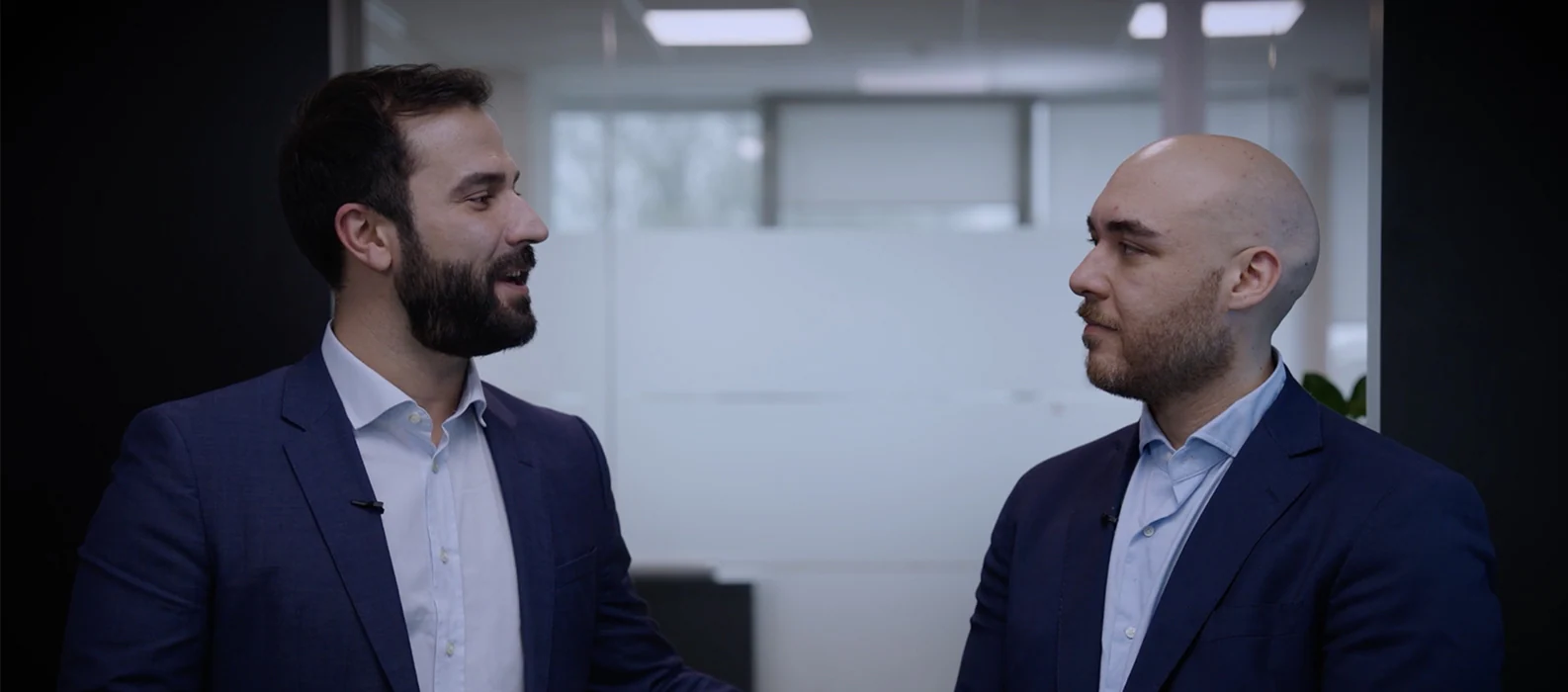 Two colleagues from different generations at Lamborghini share stories and insights during a coffee break, highlighting the value of diverse perspectives and fostering continuous learning.