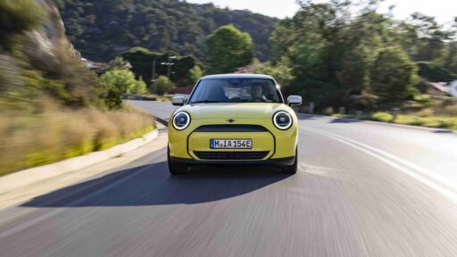 The all-electric MINI Cooper E in Sunny Side Yellow features white roof and mirror caps, 17″ U-Spoke rims, and a sporty interior, perfectly matching Greece's Mediterranean charm.