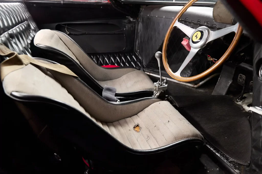 A legendary Ferrari 250 LM by Scaglietti, with a winning history at Le Mans, is up for auction at £20M. Despite scuffs and a ripped seat, it’s a collector’s dream.