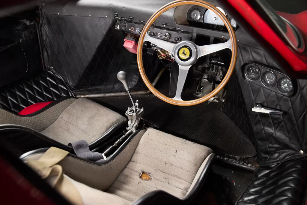 A legendary Ferrari 250 LM by Scaglietti, with a winning history at Le Mans, is up for auction at £20M. Despite scuffs and a ripped seat, it’s a collector’s dream.